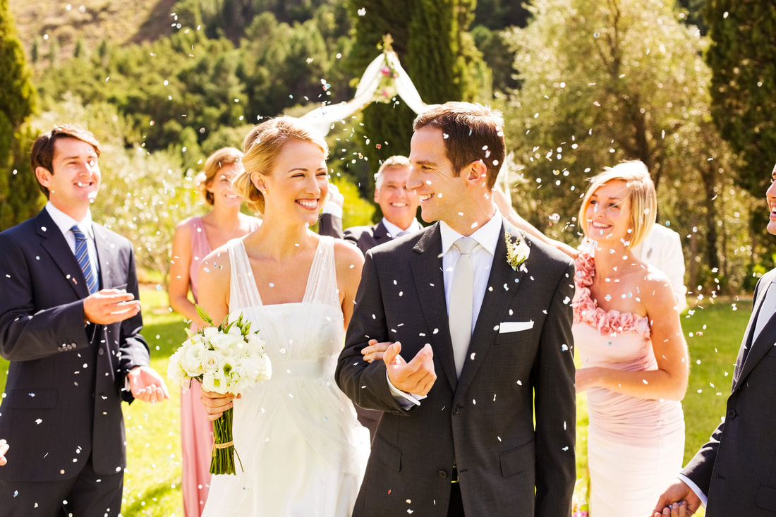 Guests Throwing Confetti On Couple During Garden Wedding